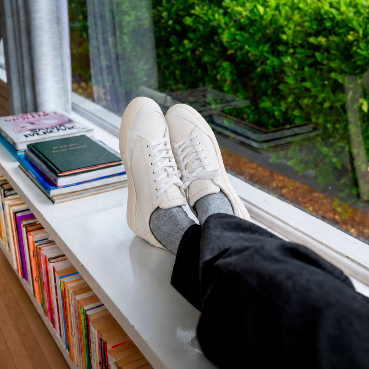 CLAE NELSON White Off-White worn with grey socks by a window